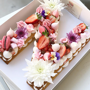 This cake can be shaped into any letter and is filled with the buttercream of your choice. We top off this unique cake with berries, flowers, and french macaroons.