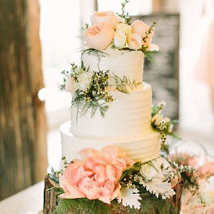 This is one of our wedding cakes. It is completely customizable and features edible flowers that are delicately placed all around. This cake is perfect for any newlywed couple to enjoy together on their special day.